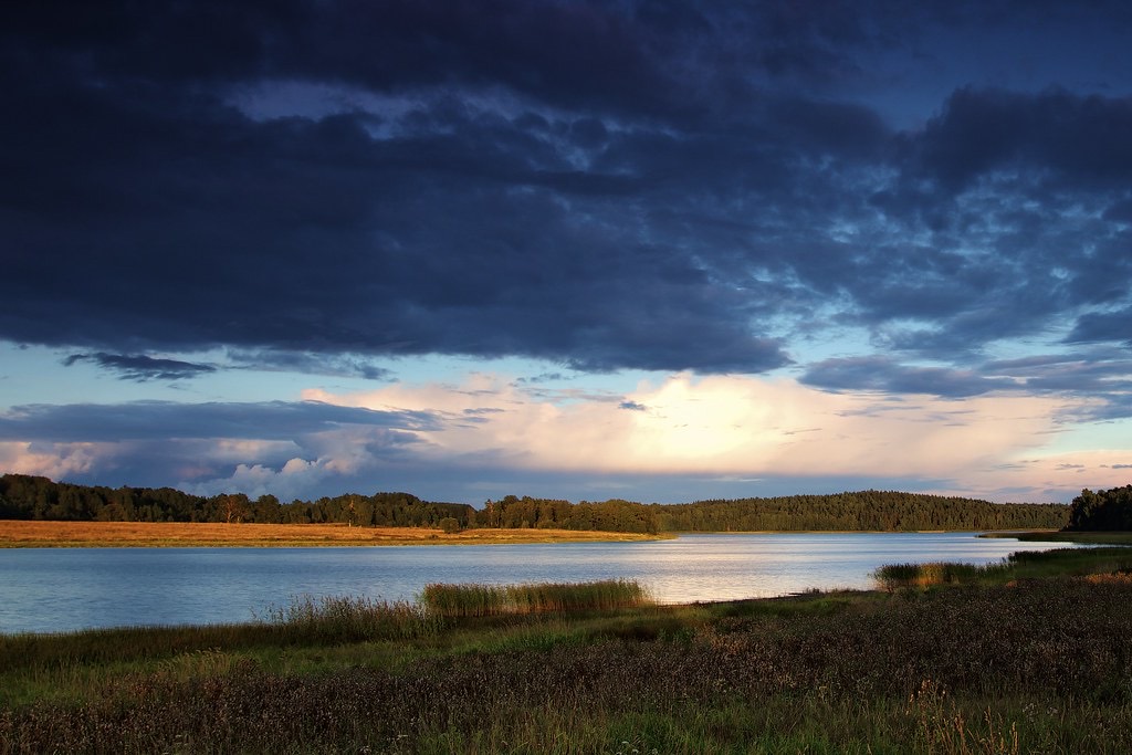 First light breaking through clearing clouds over still water